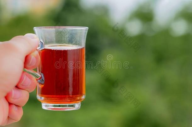 手拿土耳其的茶水杯子和绿色的背景