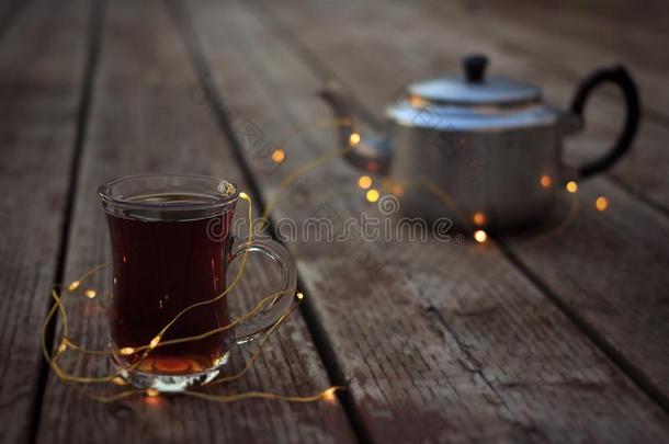 古老的茶水壶和玻璃马克杯关于热的茶水被环绕着的在旁边家畜的肺脏