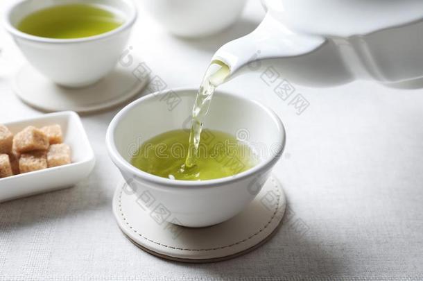 传布绿色的茶水<strong>进入</strong>中白色的瓷杯子