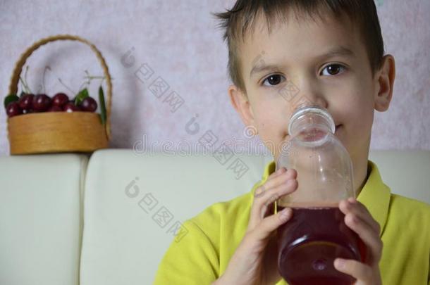 漂亮的小的男孩喝饮料果汁在家,樱桃果汁饮料从
