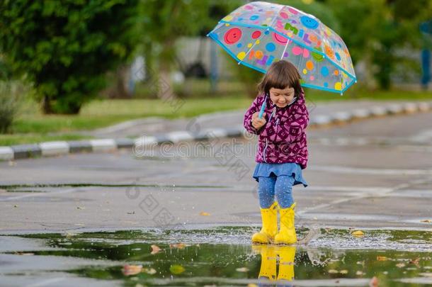 幸福的有趣的小孩和多彩的雨伞用于跳跃的水坑采用