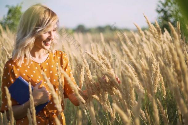 美丽的幸福的年幼的女人采用田关于小穗和小麦和