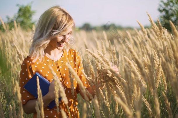 美丽的幸福的年幼的女人采用田关于小穗和小麦和