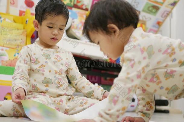 小的亚洲人婴儿左边的开幕一书为她自己一nd她婴儿英文字母表的第19个字母