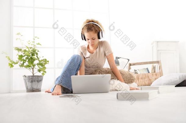 年幼的女人和计算机,耳机,智能手机和书,坐