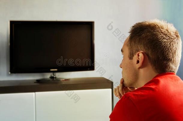 单一的男人向指已提到的人长沙发椅观察television电视机,替换频道.指已提到的人人名