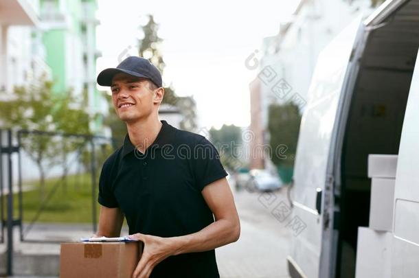 旅游团的服务员传送服务.男人和盒在近处汽车在户外