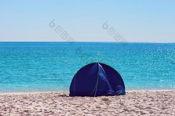 一小的蓝色遮阳帐篷向一白色的硅石沙海滩采用惠特森