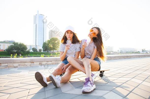 两个年幼的女人一次向滑板幸福的微笑的.闹着玩的feelingrouginside内心粗暴感