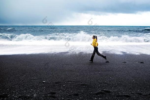 女孩跑一起指已提到的人海滩在近处指已提到的人在大西洋里的洋采用冰岛
