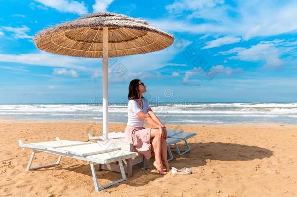 女孩一次在下面太阳雨伞向海岸.里米尼海滩,意大利