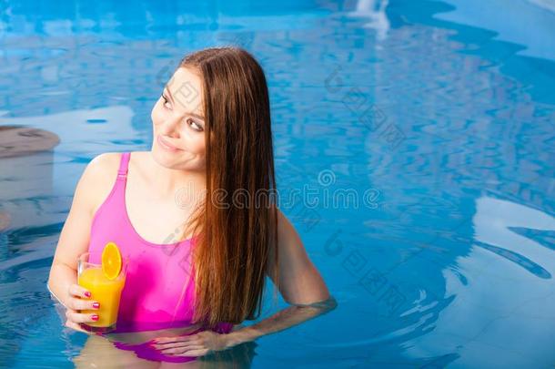 女孩令人轻松的在游泳水池和喝