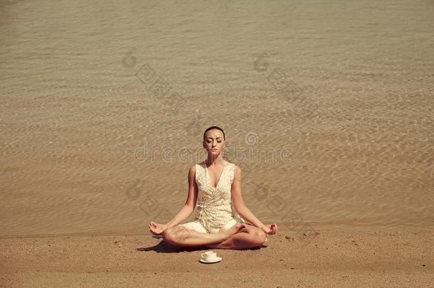 女人深思采用瑜伽使摆姿势和咖啡豆杯子在w在er