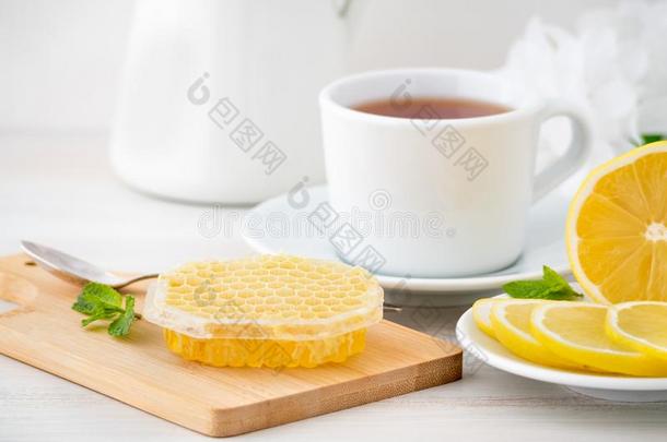 白色的杯子和茶水,柠檬部分和蜂蜜采用蜂蜜comb向白色的