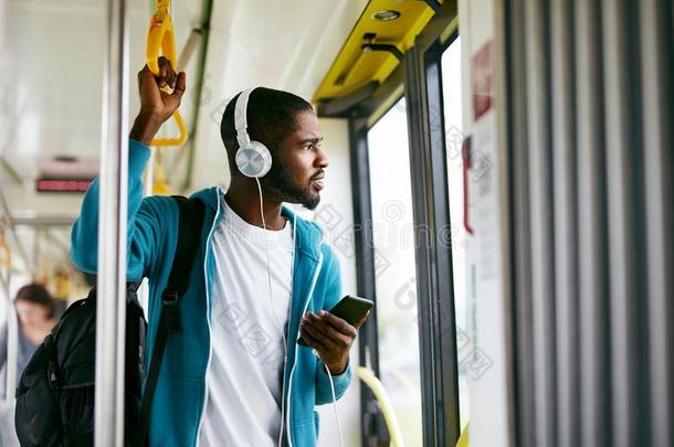 男人使用电话,收听的音乐同行的采用火车