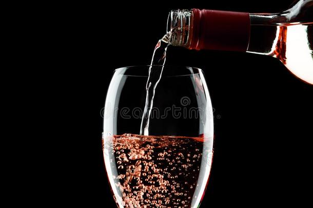 传布粉红色的玫瑰葡萄酒从瓶子向玻璃向黑的