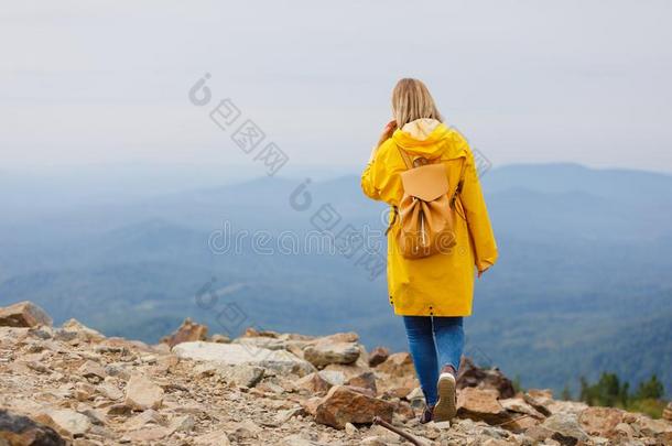 时髦的低到臀部的女人旅行支票和背包向顶关于山