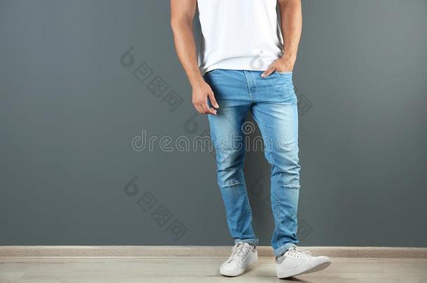 年幼的男人采用时髦的牛仔裤在近处<strong>灰色</strong>的墙和土壤-植物-<strong>大气</strong>连续体