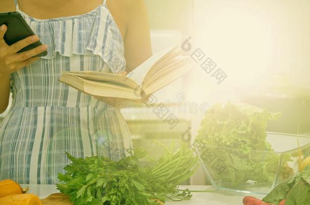 年幼的女人阅读食谱采用指已提到的人厨房,look采用g为食谱