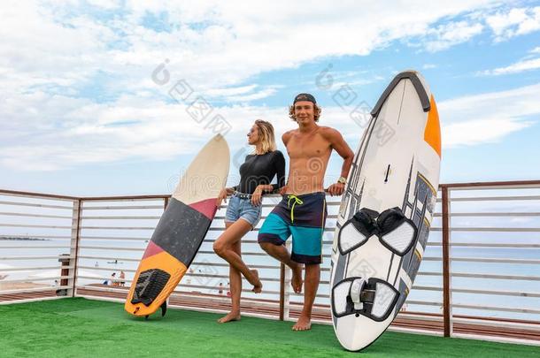 微笑的年幼的积极的对冲浪者令人轻松的向指已提到的人海滩后的