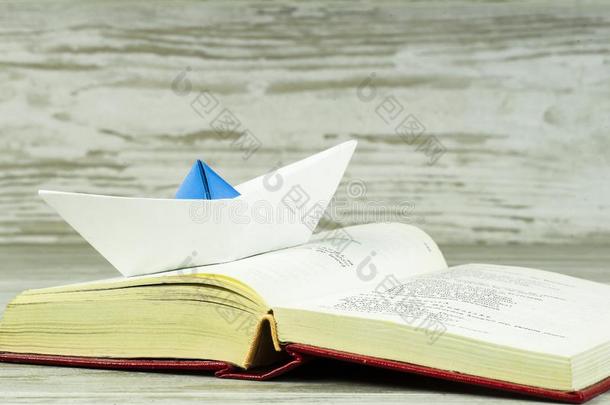 一纸船帆船运动通过一敞开的书
