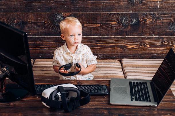 蹒跚行走的人使用便携式电脑和personal计算机个人计算机计算机.小的男孩坐在计算机wickets三柱门