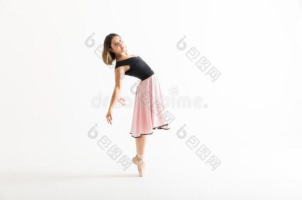 芭蕾舞女演员表演的卖艺人身体向后仰作弓状的姿势向白色的背景