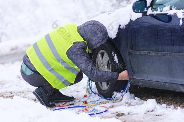 男人<strong>安装</strong>雪链向指已提到的人轮子关于<strong>汽车</strong>.