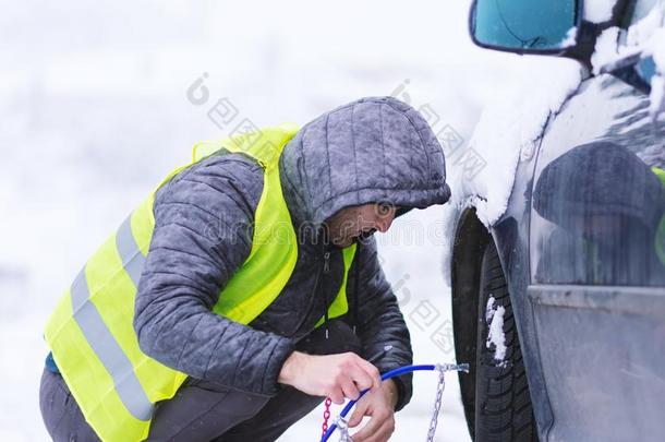 男人<strong>安装</strong>雪链向指已提到的人轮子关于<strong>汽车</strong>.