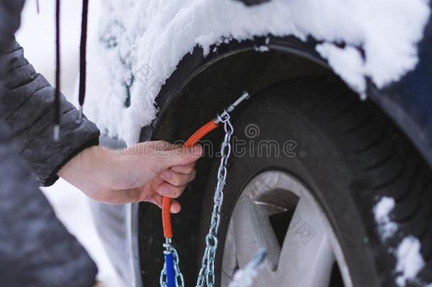 男人安装雪链向指已提到的人轮子关于汽车.