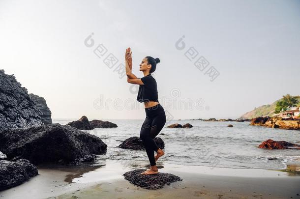 年幼的健康的女人开业的<strong>瑜伽</strong>向指已提到的人海滩在日落