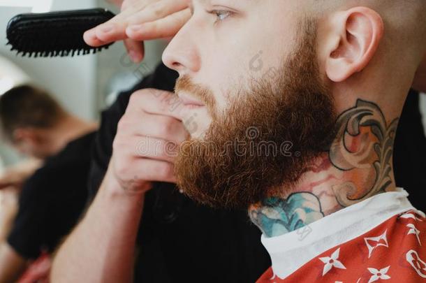 理平头的男人有胡须的刺青男人采用理发店.理发师切头发winter冬天