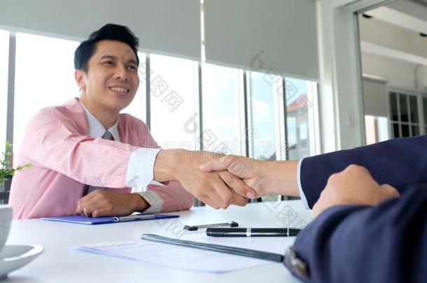 亚洲人男人握手顺利地采用工作采用terview在办公室背