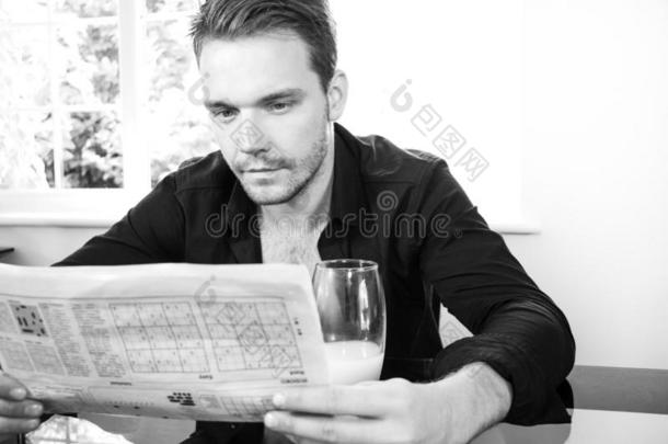 好的有样子的男人在早餐表,喝饮料和阅读新闻记者