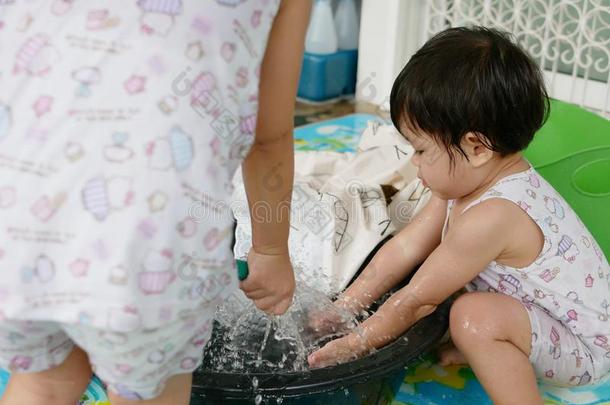 小的亚洲人婴儿女孩立刻,洗涤衣服在家