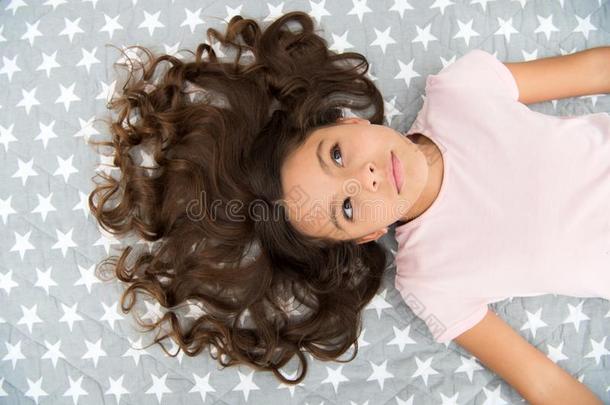 女孩小孩和长的有卷发的头发放置向床顶看法.小孩佩菲