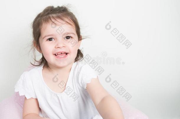 小的女孩笑的玉兰油向白色的墙