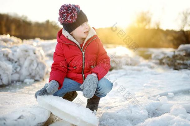 幸福的小的女孩演奏和冰赛跑者起跑时<strong>脚</strong>底所撑的木块在旁边冷<strong>冻</strong>的河在的时候