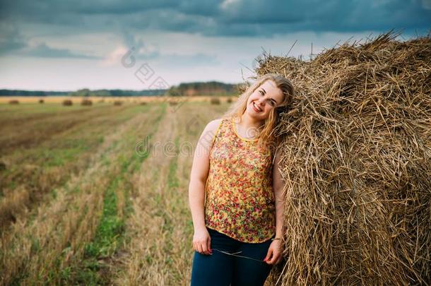 肖像美丽的加大小年幼的女人起立在近处干草大包