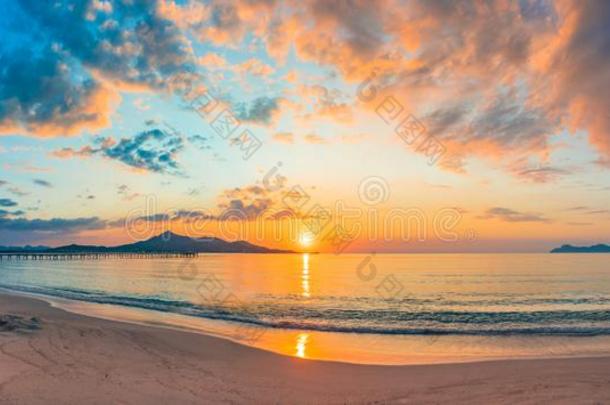 日落全景画在海滩和田园诗般的太阳在地平线和云服务