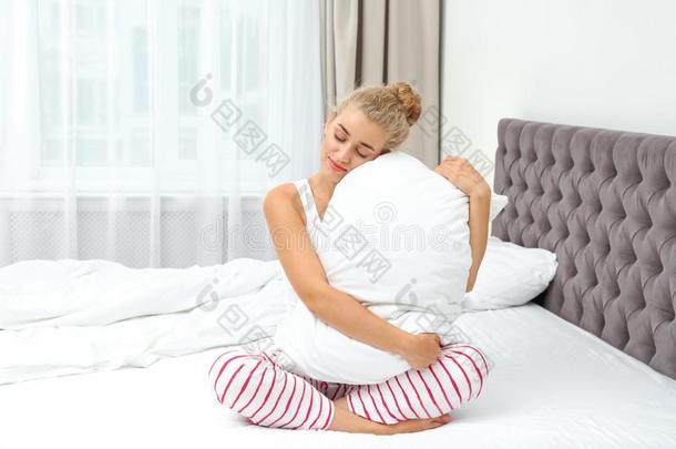 年幼的女人热烈地拥抱枕头向床