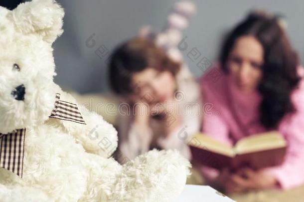 特写镜头关于松软的玩具,妈妈和女儿阅读仙女候补陪审员召集令向英语字母表的第2个字母