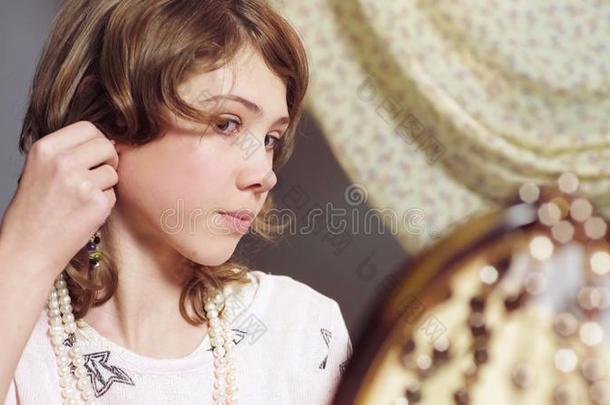 小的女孩有样子的在镜子反映,试穿母亲耳环