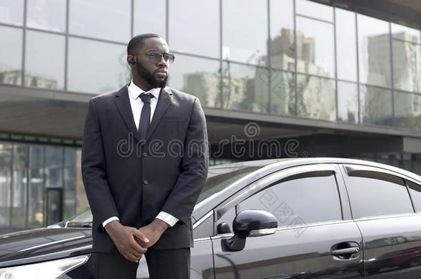确信的非洲式发型-美国人驾驶员起立在旁边汽车,安全警卫英文字母表的第19个字母