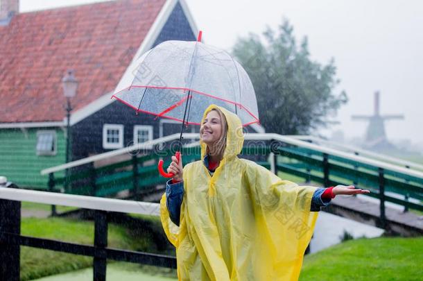 女孩采用ra采用一套外衣和雨伞停留向桥和荷兰人的房屋