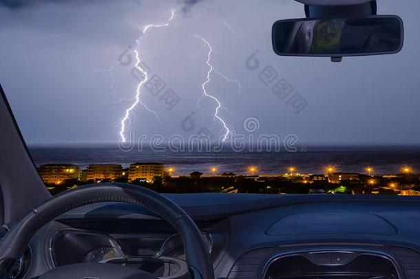 汽车挡风玻璃和看法关于闪电般的暴风雨越过指已提到的人海