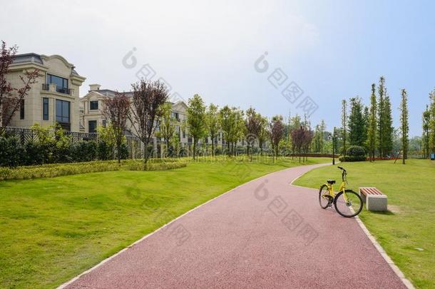 黄色的自行车向红色的小路采用草地al向g围以栅栏住宅采用和煦的：照到阳光的总数