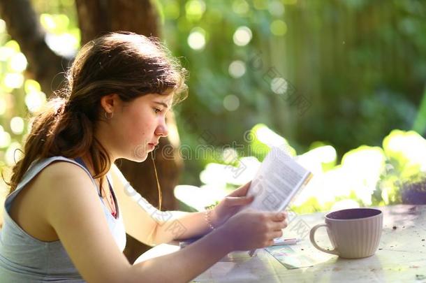 十几岁的青少年学生女孩阅读书和茶水杯子