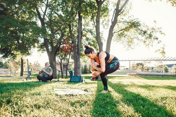 中部年龄女人做瑜伽采用公园在外面向日落