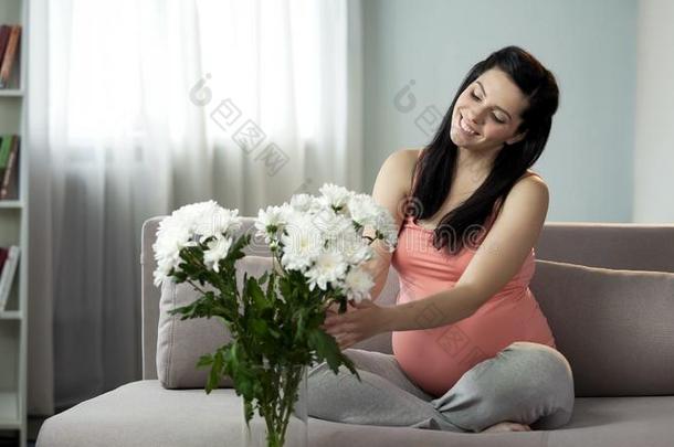可爱的怀孕的女士装饰房屋和美好的花,美感